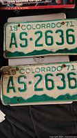 Two 1971 Colorado license plates with green text on white background, registration number AS-2636. Plates show wear and some rust around holes.