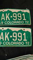 Two green and white 1972 Colorado license plates with AK-991 embossed, showing front face and detail of condition