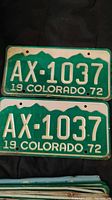 Two 1972 Colorado license plates with registration AX-1037 stacked, showing front side with green background and white embossed lettering.