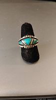 Front view of the 925 vintage handmade Navajo turquoise inlay ring on a black ring stand.