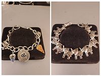 Two silver-tone charm bracelets placed side by side on a black cushion. Left bracelet has NYC and other assorted charms; right bracelet features multiple elephant charms.