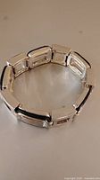 Silver-tone stainless steel bracelet with rectangular links laid flat to show shape and design.
