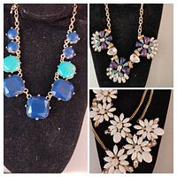 Three vintage gold tone necklaces displayed on black busts, showing detailed views of blue and turquoise geometric stones, purple and green floral clusters, and white floral opaque stones with clear accents.