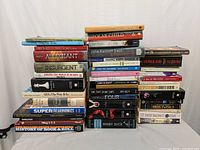 Photo showing the entire lot with multiple stacks of novels and instructional books, including visible titles like Allegiant, Insurgent, Moby Dick, and The Rolling Stone History of Rock & Roll.