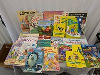 Lot of children's early reader books arranged on a white cloth background showing titles and conditions, photographs include front covers with colorful illustrated designs.