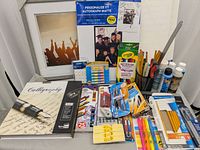 Full view of all items including framed canvas, calligraphy book, crayons, markers, pencils, scissors, paint bottles.