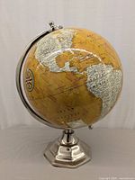 Full view of the decorative globe showing North and South America, metal base, and stand