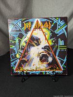 Front cover of Def Leppard 'Hysteria' album featuring colorful artwork with screaming face and geometric triangular design.