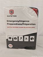 Front of the sealed box showing the Safeton brand, emergency preparedness and first aid kit labeling, with icons representing various emergencies and indication of 156 pieces included.