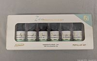 Front view of Zen Essential Oils 6-pack box showing the six bottles through clear window labeled with oil names.