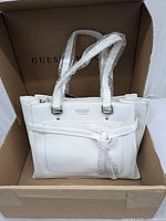 Full view of satchel inside original box with plastic wrap on handles