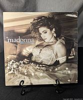 Front cover of Madonna 'Like A Virgin' vinyl record album featuring Madonna in a lace top and tulle skirt, placed on a stand, showing wear on corners and edges.