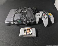 Front angle of Nintendo 64 console with one wired gray controller and GoldenEye 007 game cartridge visible in front.
