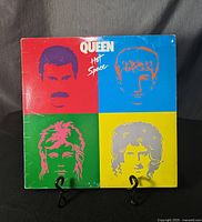 Front cover of the Queen Hot Space vinyl record showing colorful artwork of band member faces in four quadrants.