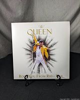 Front cover of the Queen vinyl record "Rock You From Rio - Live!" showing Freddie Mercury in a yellow jacket on stage.