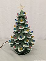 Front view of vintage ceramic Christmas tree decorated with multi-color bulbs and a star topper