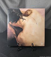 Front cover of vinyl record featuring Harry Styles' back with visible tattoos and necklace, displayed on a stand against a dark background.