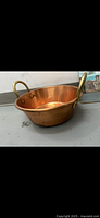 Side angle view of copper bowl showing the gold handles and copper surface.