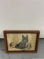 Front view of framed black and white dog artwork featuring a Scottish Terrier lying down, signed by the artist.