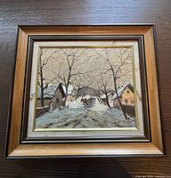 Front view of framed oil painting depicting winter village scene