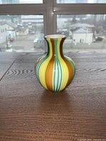 Front view of Murano glass swirl vase on wood surface with cityscape background.