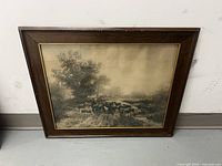 Photo of framed antique art showing a sheep herd in a rural landscape, captured from a slight angle.