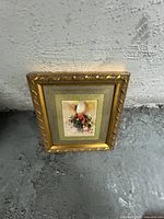 Photo of floral painting with gold ornate frame showing the artwork and frame details