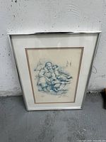 Framed signed artwork featuring three seated figures in blue ink and pencil, signed by artist with edition number visible. Silver metal frame with glass and double matting.