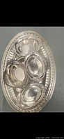 Photo shows the silver set including four matching serving dishes arranged inside one large oval serving tray with decorative borders.