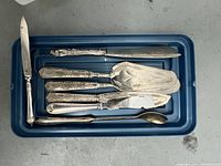 Top-down image showing all seven pieces arranged in a blue plastic tray, highlighting the variety of utensils and handle designs.