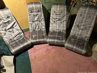 Four gray plaid fabric rocking gaming chairs on floor arranged in a semicircle.