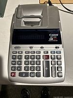 Top view of Canon MP11DX calculator showing keypad, display, and printer section with power cord connected.