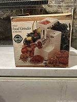Front of the original box showing the Maverick electric food grinder with images of ground meat and vegetables