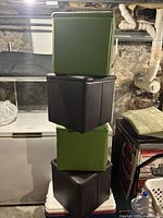 Stack of four faux leather storage cubes alternating in green and dark brown/black.