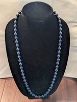 Front view of Monet dark blue beaded necklace on display bust