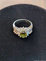Front view of ring showing round green peridot center and clear accent stones on white gold band