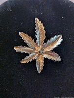 Front view of the gold tone brooch, showing detailed leaf veins and central accent.