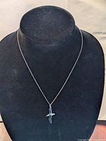 Front view of sterling silver chain necklace with a seagull-shaped enamel pendant on a black jewelry display bust.