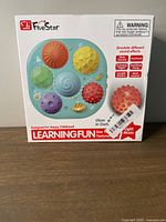 Front of box showing seven textured balls in bright colors with details about light and music features and sound effects such as rain, heartbeat, and birdsong