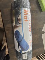 Photo of the rolled and packaged black exercise mat with brand label visible.