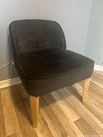 Side angle of dark blue modern accent chair showing upholstery texture and wooden legs.