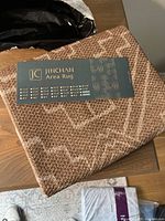 Folded jute area rug in original packaging with brand label JINCHAN visible.