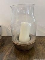 Side view of wooden candle holder with curved glass and used white candle inside.