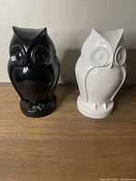 Photo showing the pair of black and white resin owl figurines side by side on a wooden surface.