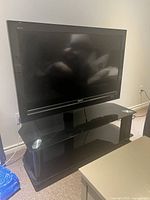 Sony 46-inch TV on black glass and metal stand, angled view showing screen and reflection.