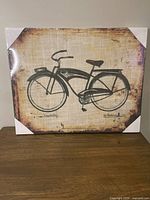 Front view of the canvas print showing the full vintage green city bicycle illustration with aged beige background and signatures.