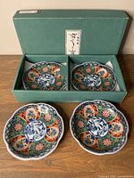 Set of four vintage Japanese Arita ware porcelain coasters inside original green box with Japanese label on lid. The box is open and the coasters are visible.