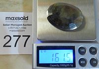 Photo of the faceted brown sapphire gemstone on a digital scale showing a weight of 161.5 carats.