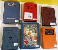 Six antique and vintage hardcover books laid out on a white surface showing titles, authors and years written on stickers