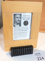 Framed wooden display featuring the ancient coin and printed historical info placed on black segmented stand.